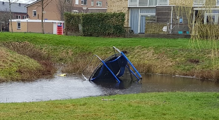 Wind blaast trampoline en speelgoed in vijvers