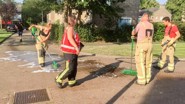 Brandweer reinigt wegdek onder een felle zon in Assen-Oost